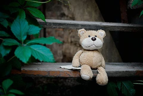 Un ours en peluche assis sur une marche d'escalier attendant l'enfant qui voudra bien de lui
