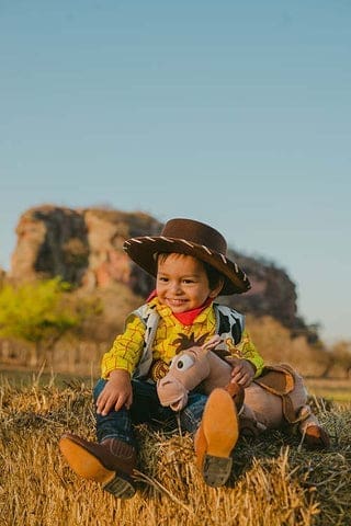 Un enfant dans éla pleine habillé en verson western avec sa peluche cheval pour l'accompagner sur la route de la vie